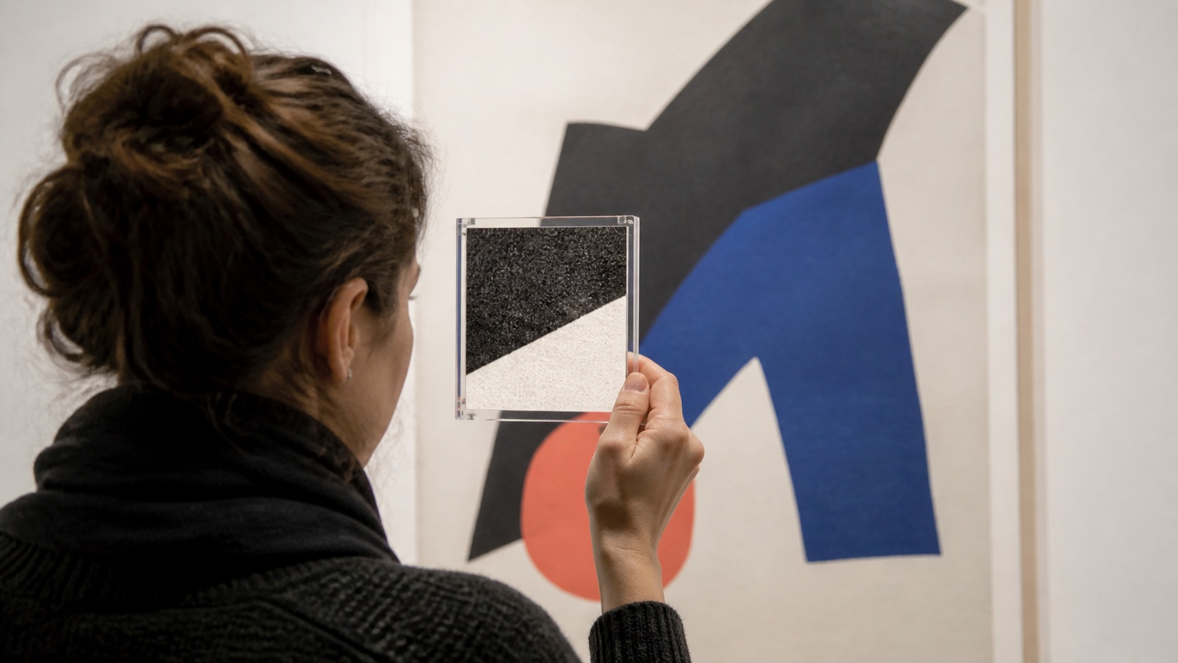 Museum visitor holding a clear viewing frame over an abstract print